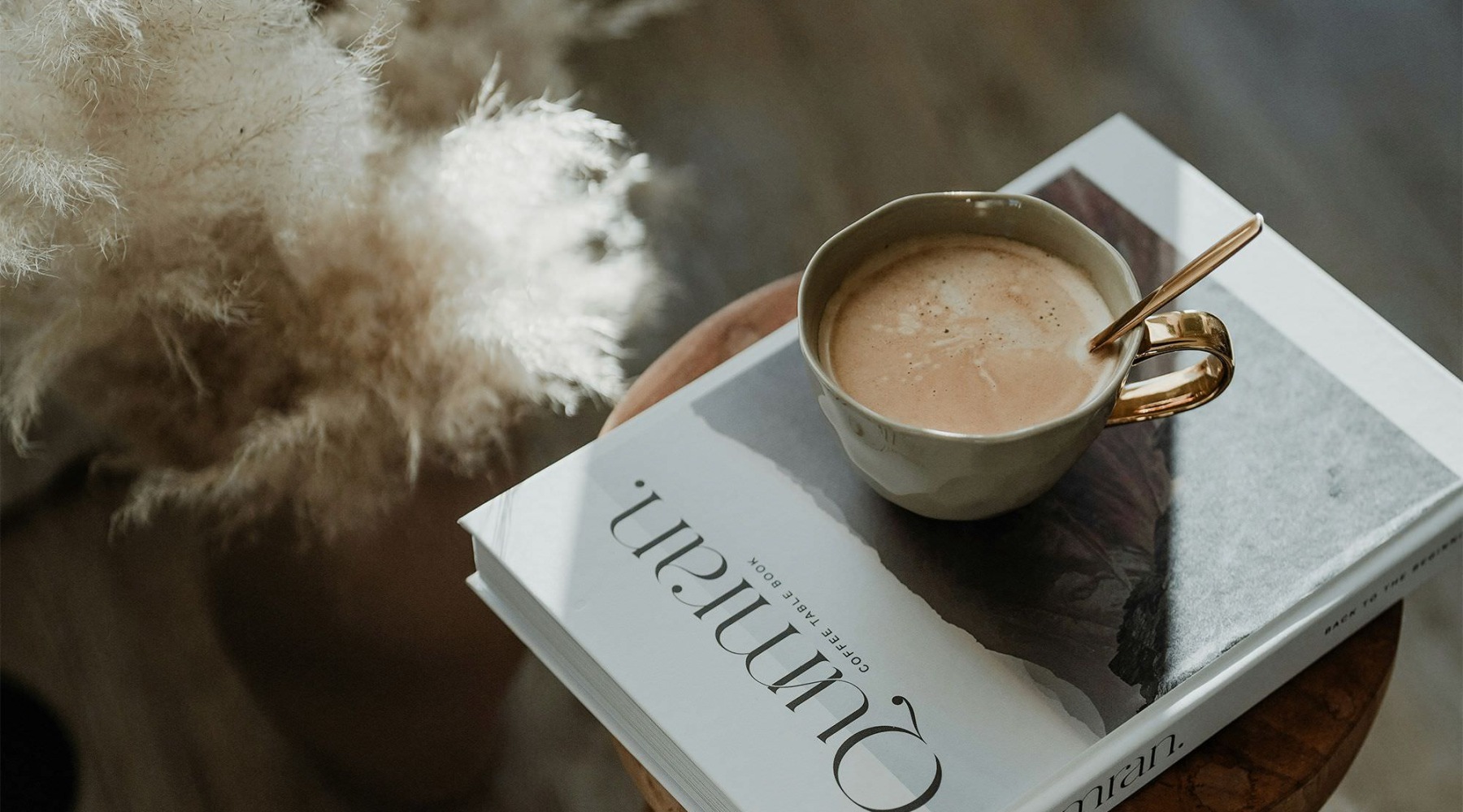 a cup of coffee on a book on a stool in a living room