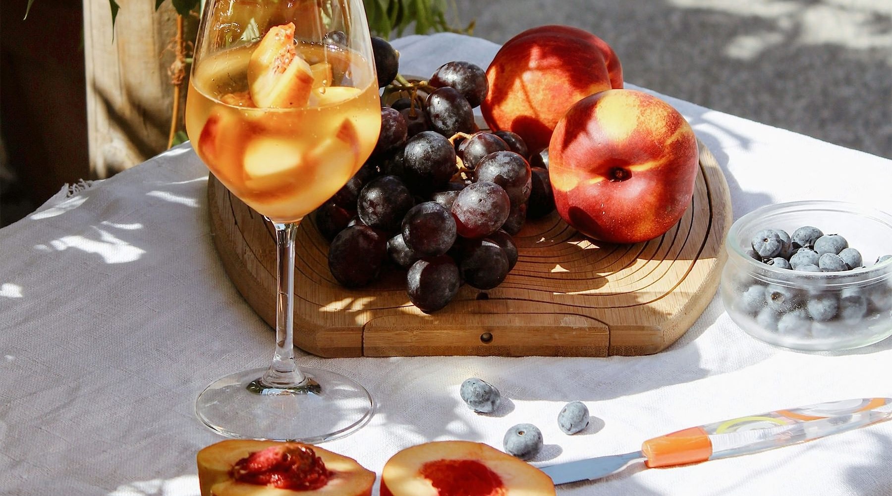 a board of fruit and a glass of wine